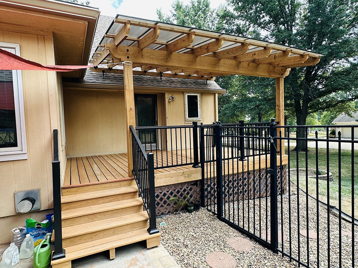 Modern wood deck with black railing and pergola by KC Outdoor Spaces in Kansas City