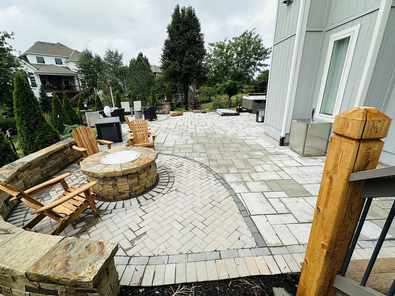 Luxury paver patio with custom stone fire pit and curved seating wall built by KC Outdoor Spaces in Kansas City